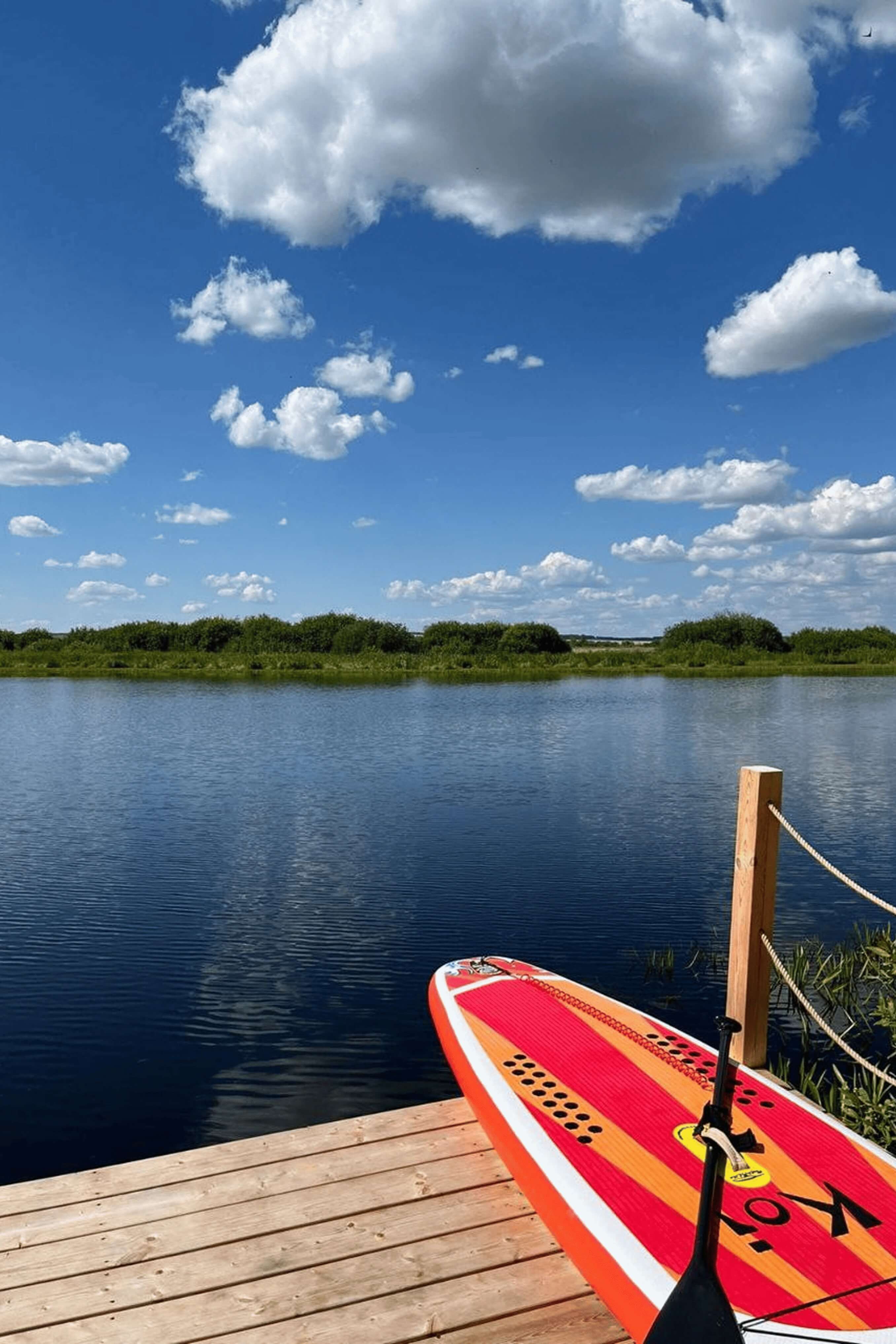 Сап-борд привязан к деревянному причалу на озере.