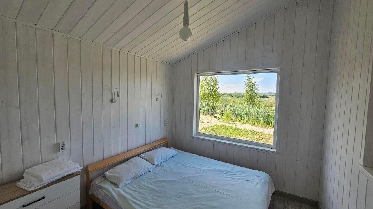 Спальня с кроватью и панорамным окном на природу.