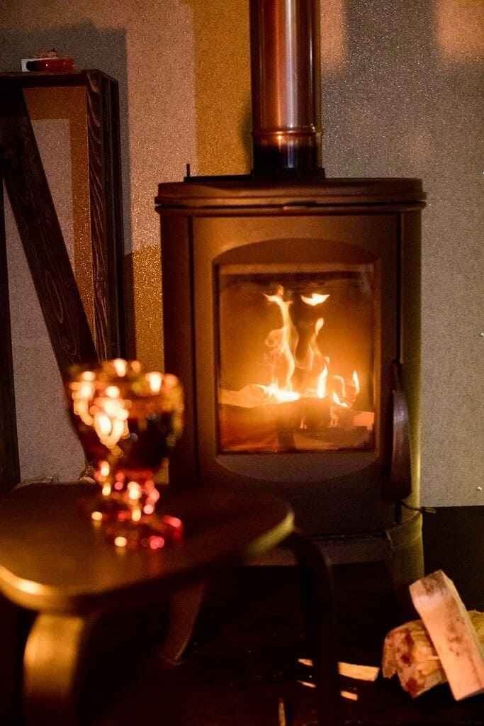 Печь-камин с живым огнём и декоративными свечами в интерьере.