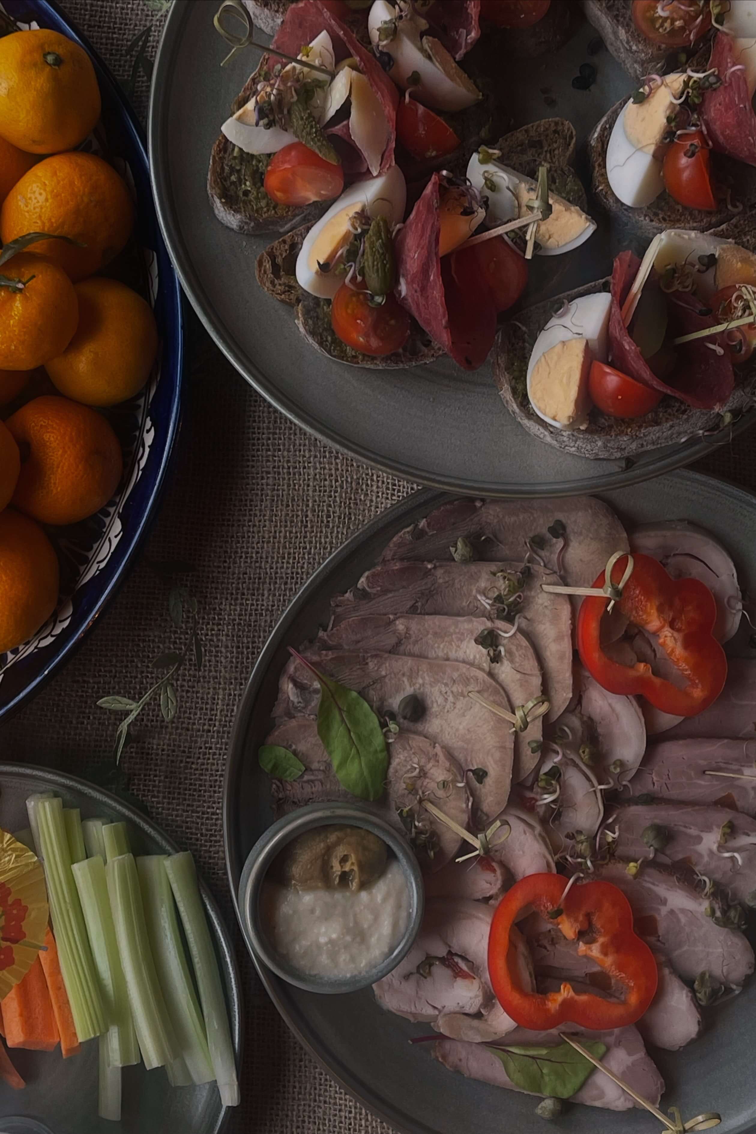 Сервировка обеда с мясными нарезками и свежими овощами.