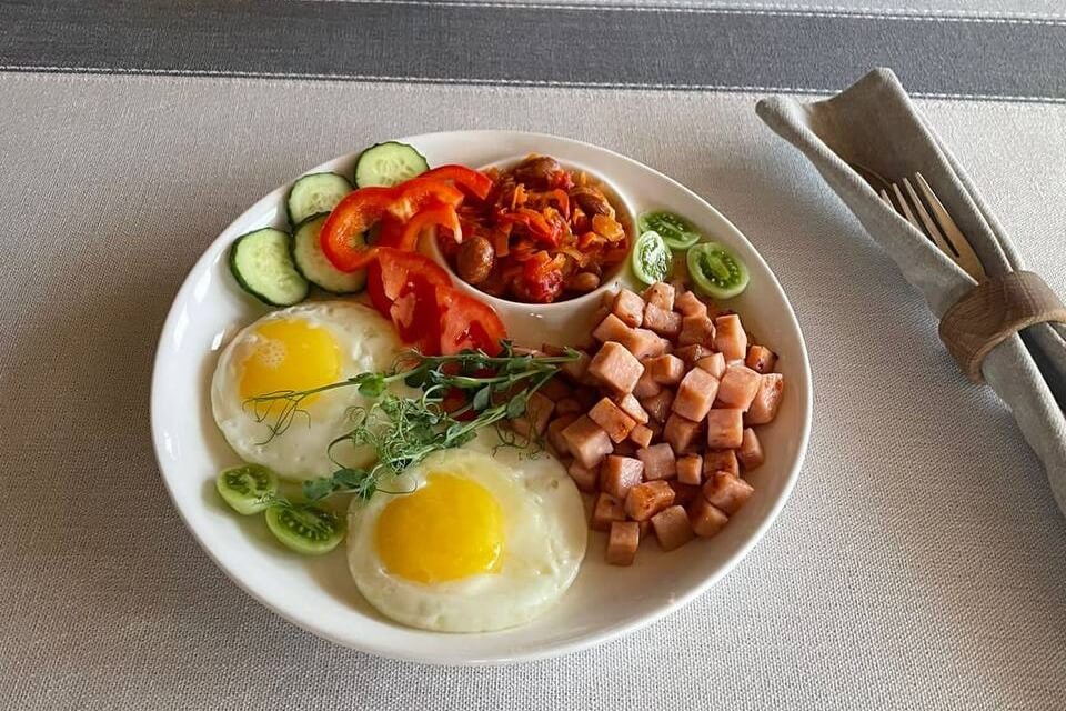 Завтрак с жареными яйцами, беконом и свежими овощами.