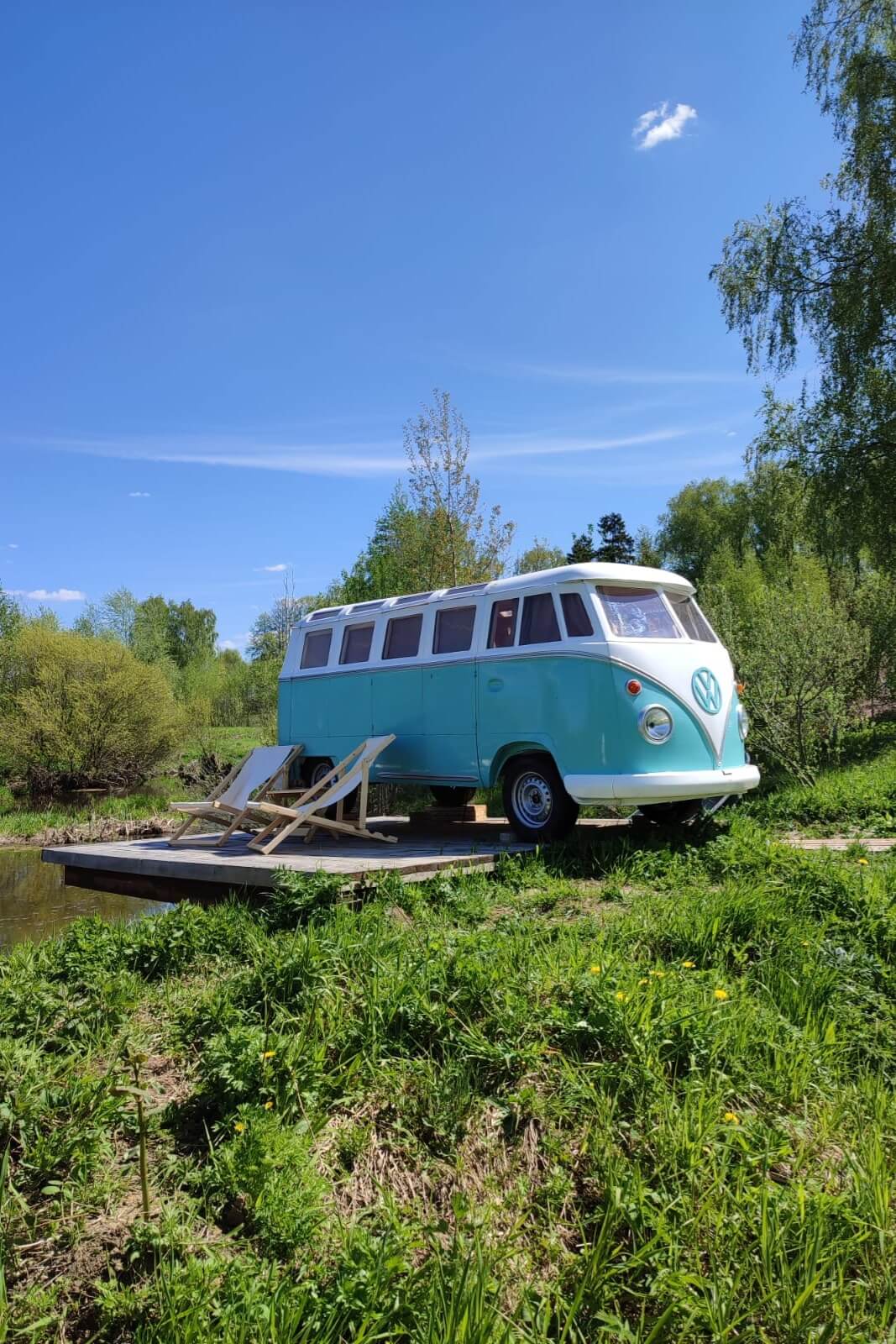 # Alt-текст для фотографии:

Бирюзовый микроавтобус Volkswagen на деревянной палубе у воды.