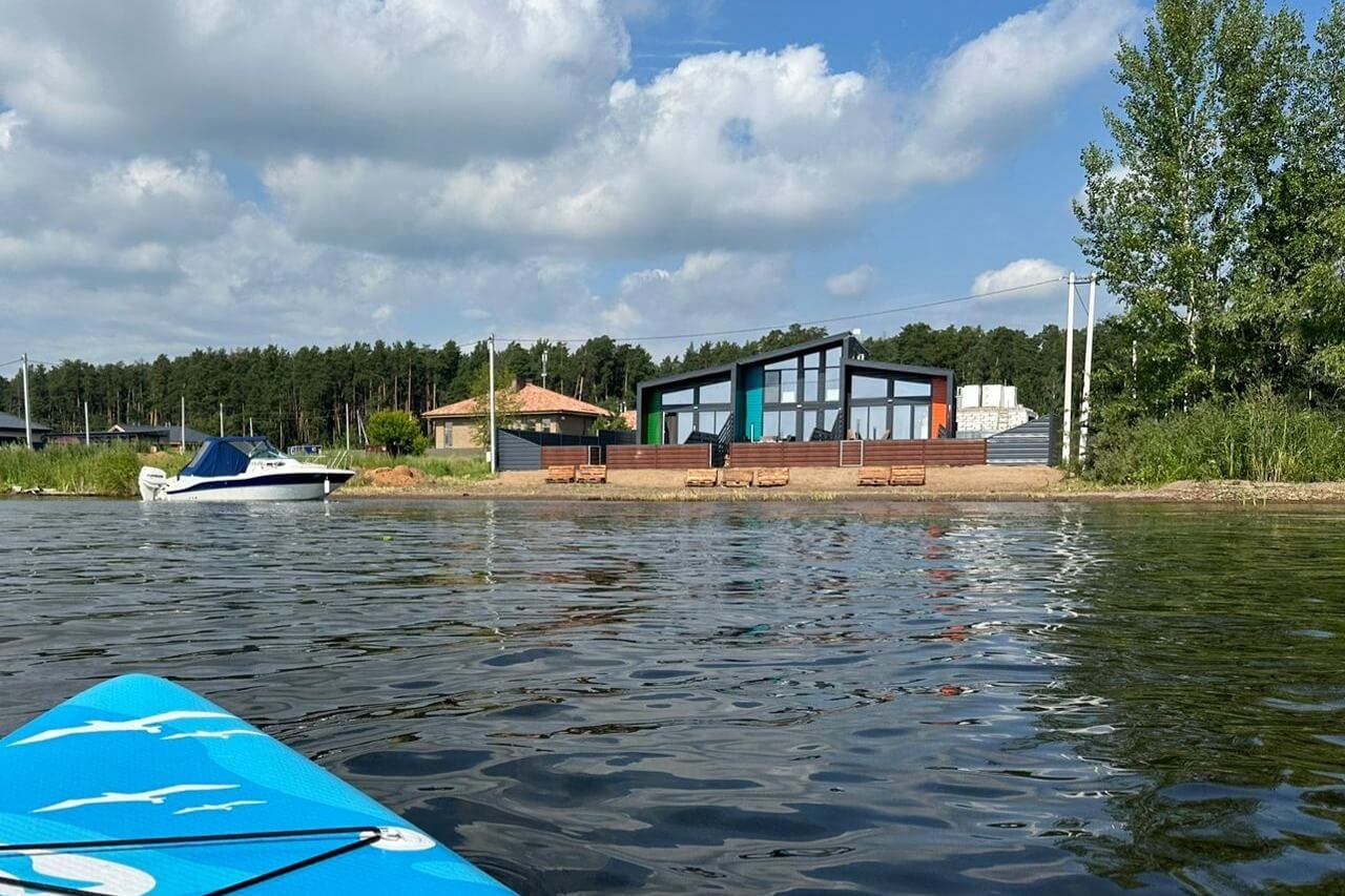 Вид на каркасный дом с террасы, река и лес.
