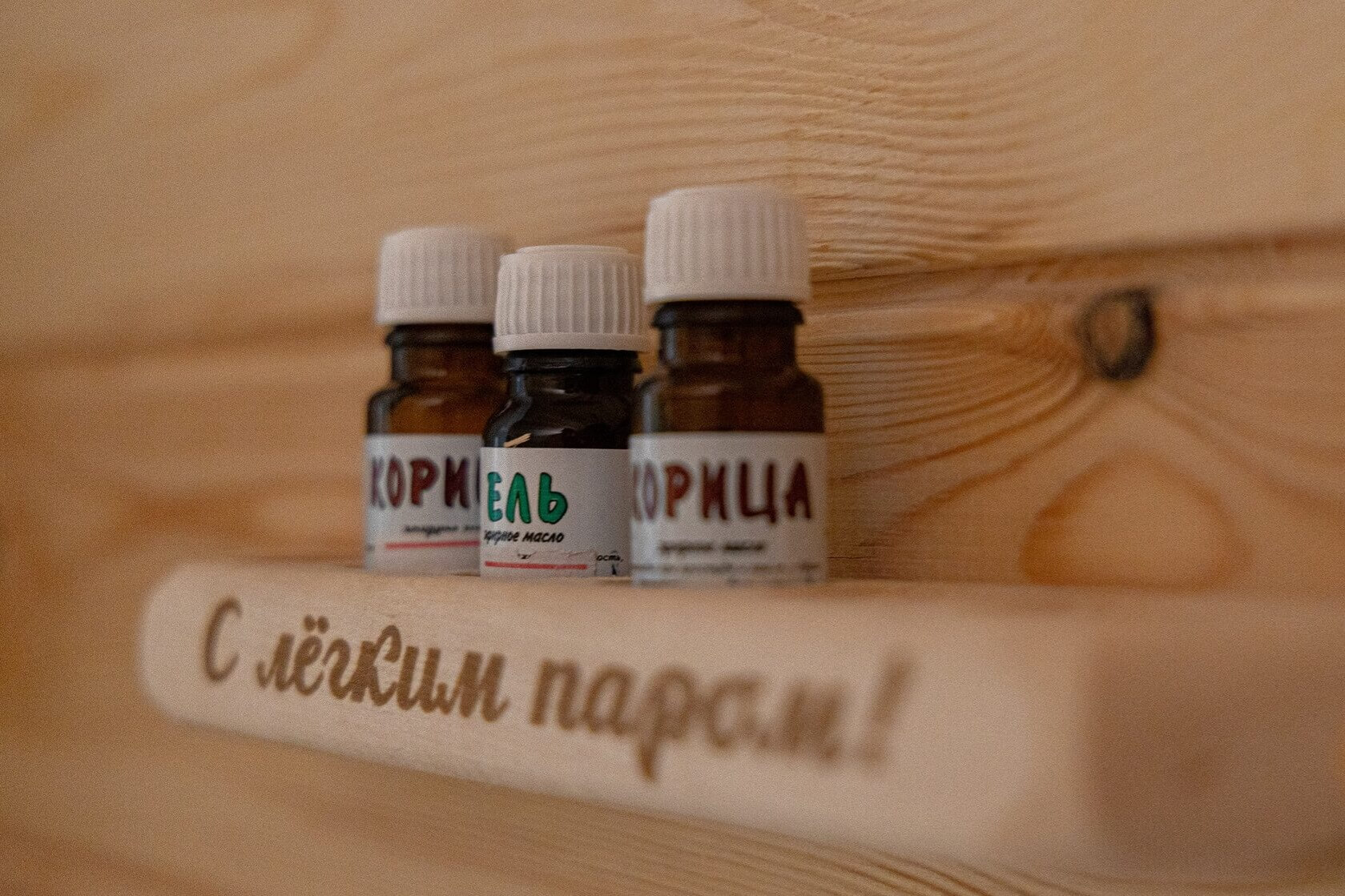 Эфирные масла с ароматическими надписями на деревянной полке.