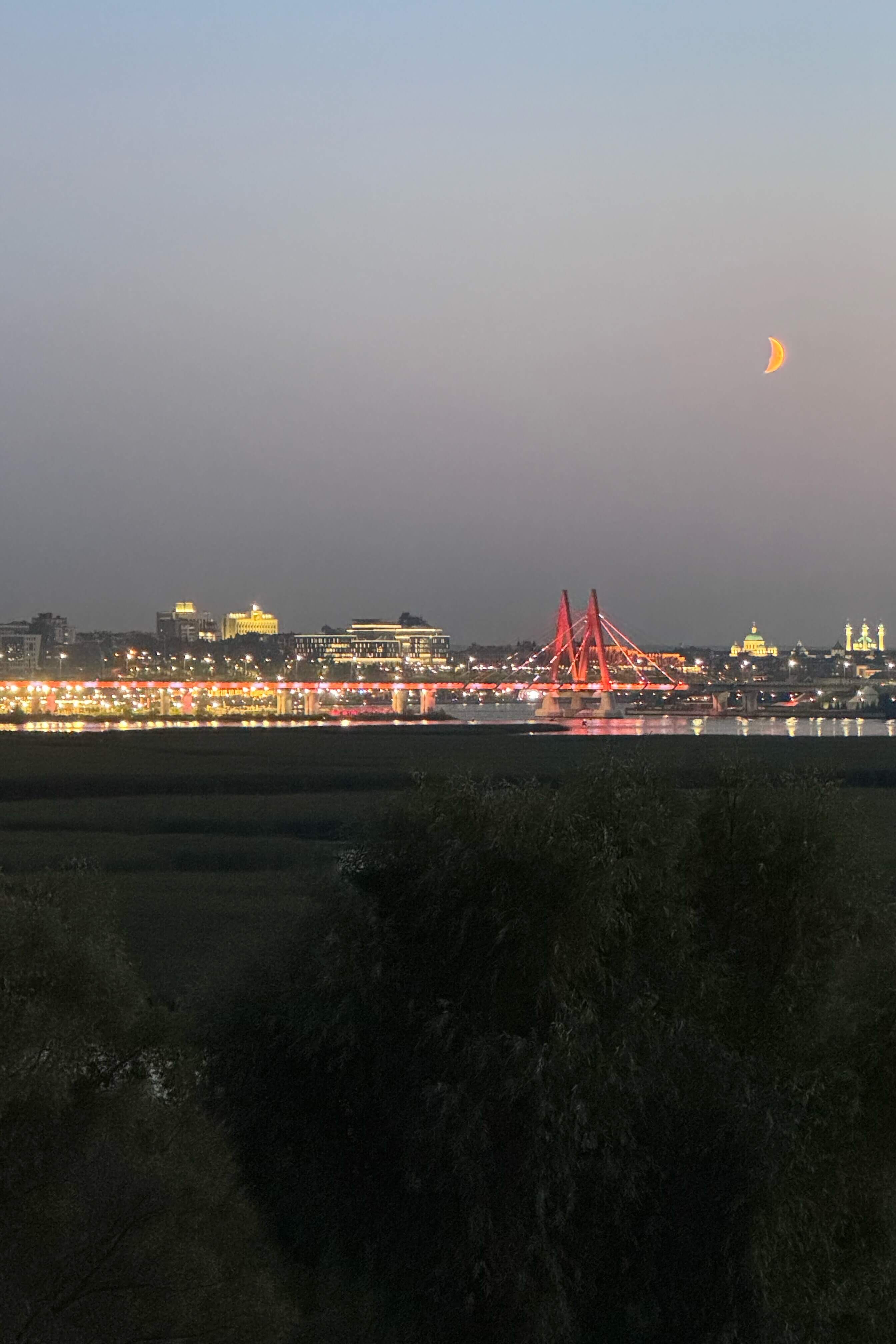 # Ночной вид на красный мост через реку с подсветкой.