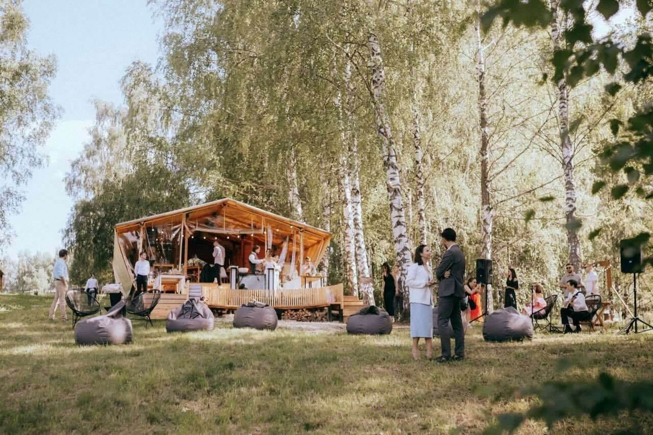Оранжевый шатёр на фоне берёзовой рощи с гостями.