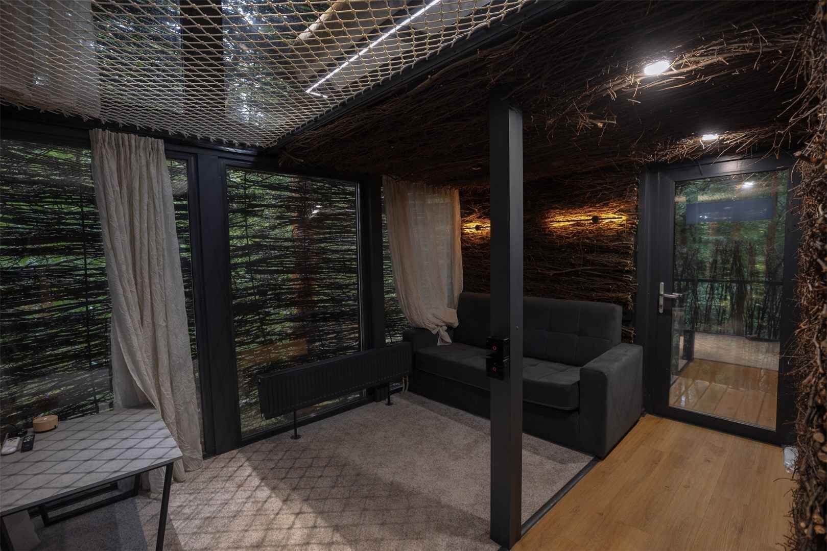 # Alt-текст для фотографии:
Спальня с чёрными колоннами, кроватью и панорамными окнами на лес.