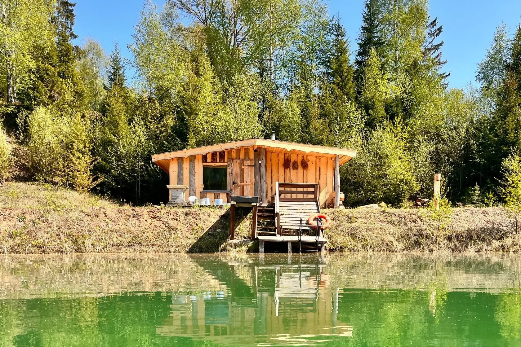 Округлый деревянный дом на воде среди лесов.