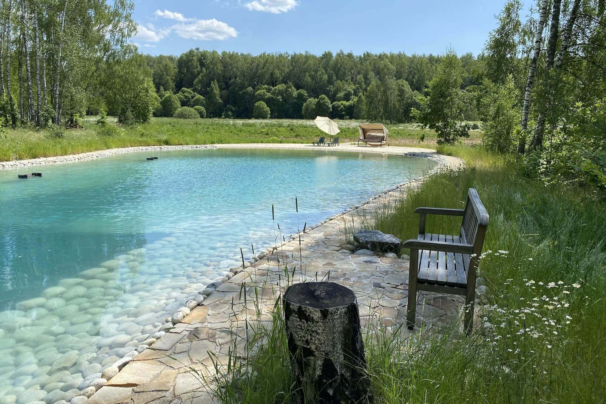 Озеро с прозрачной водой, деревянные кресла на берегу.